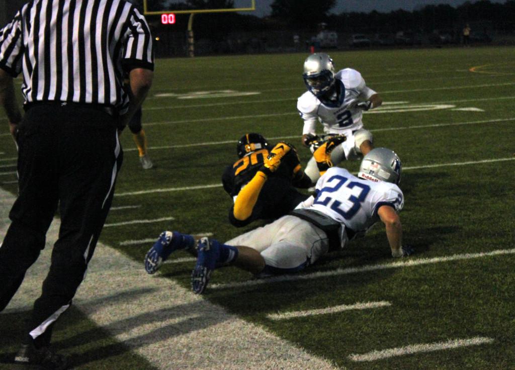 Senior running back Deron Thompson is tackled by two Kapaun players.