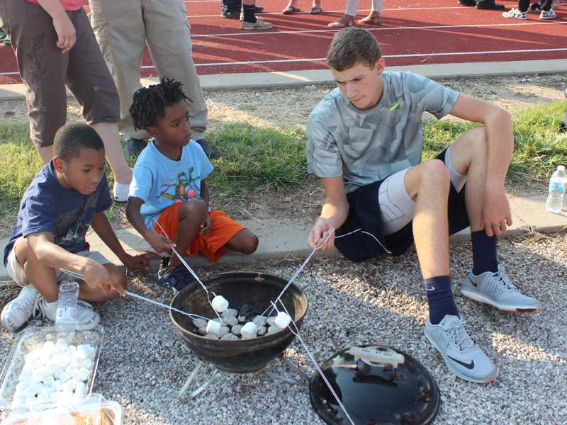 Sophomore Tanner David roasts marshmallows with two Open House attendees at the Language Arts booth. Photo by Walters