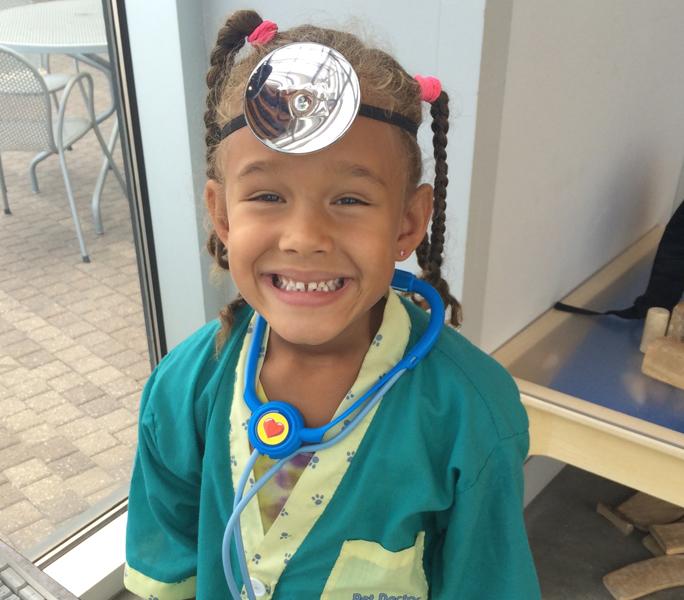 Karissa Kai Patterson, Keyanna Patterson's younger sister, grins in the Veterinarian Clinic exhibit in the Exploration Place. 