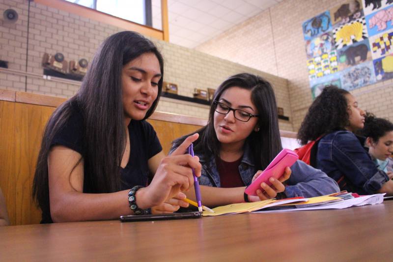 AVID students Irene Delarosa and Fabiola Delatorre work on homework together during lunch. AVID is one of many programs at risk of being cut due to budget constraints.