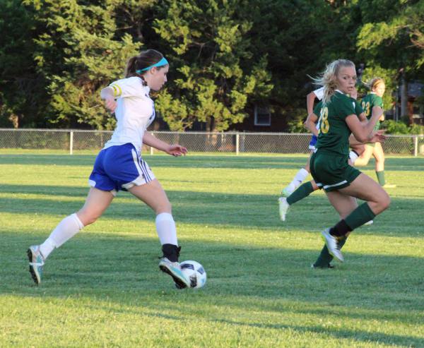 Kick it up a notch. Junior Whitney Weiford kicks the ball toward her teammate while trying to guard it from an opposing player on Tuesday at the Varsity soocer game against Bishop Carroll. Prior to the game, the soccer team could not warm up due to senior night, but still tried their best. "I was very confident going into the game, but as soon as they got ahead of us, I knew it was going to be a struggle, but I knew we couldn't give up," Weiford said. 