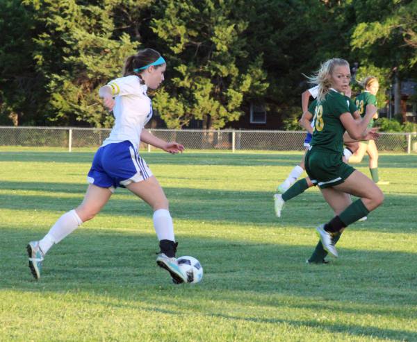 Kick it up a notch. Junior Whitney Weiford kicks the ball toward her teammate while trying to guard it from an opposing player on Tuesday at the Varsity soocer game against Bishop Carroll. Prior to the game, the soccer team could not warm up due to senior night, but still tried their best. I was very confident going into the game, but as soon as they got ahead of us, I knew it was going to be a struggle, but I knew we couldnt give up, Weiford said. 