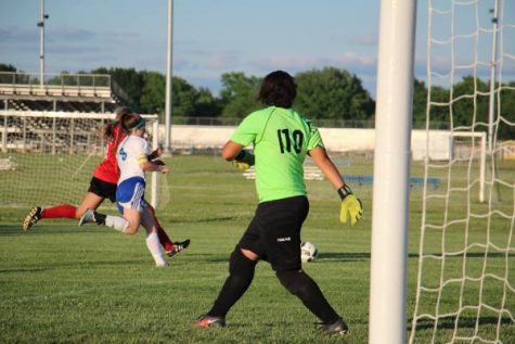 Defender Whitney Weiford (11) fights to beat Maize player to ball as goalie Nia Baker (9) prepares.