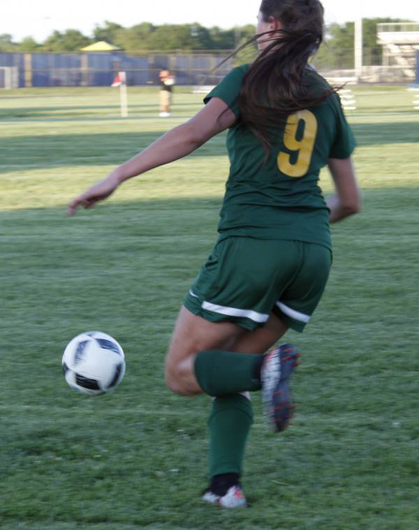 Bishop Carroll sophomore, Hanleigh Allen, kicks the ball soccer ball toward her teammate. 