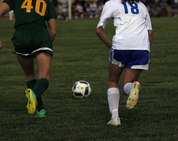 Bishop Carroll sophomore, Whitney Bockover, and Northwest freshman, Brittan Murray, race to kick the ball.