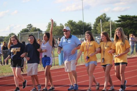 Sophomore Emmy Rodriguez flashing the peace sign as she leads the women's golf team down the track.