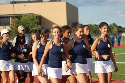 The women's tennis team marching in unison as they hear their sport being called.