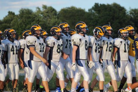 The freshman football team hold hands before they make it to the track.