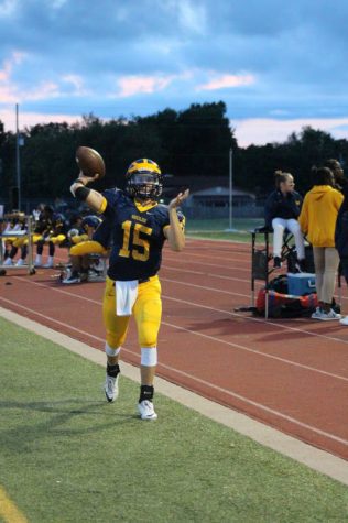 Junior Austin Anderson warms up on the sidelines by passing the ball.