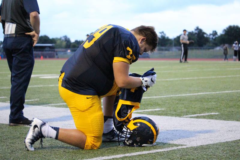 Senior Kody Atlee kneels down and prays before the game.