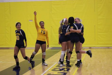 Varsity volleyball team cheering for each other after receiving a point.