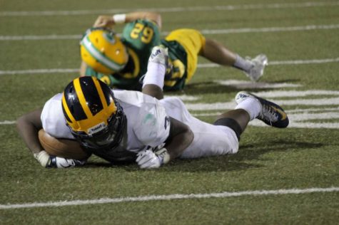 Senior Jahlyl Rounds lies on the ground protecting the ball after being tackled.