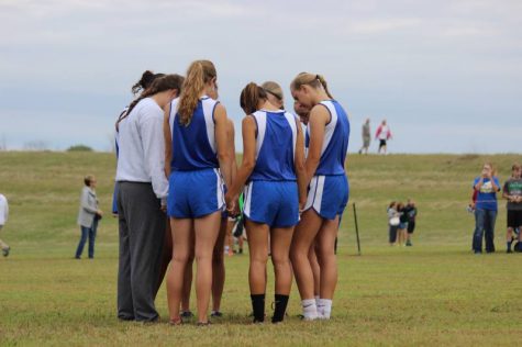 The girls varsity cross country team huddles up to pray before the race.