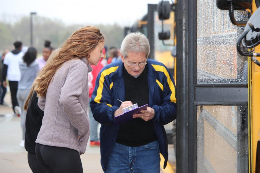 Counselor Scott Cathey checks students permission slips as they load the bus.
