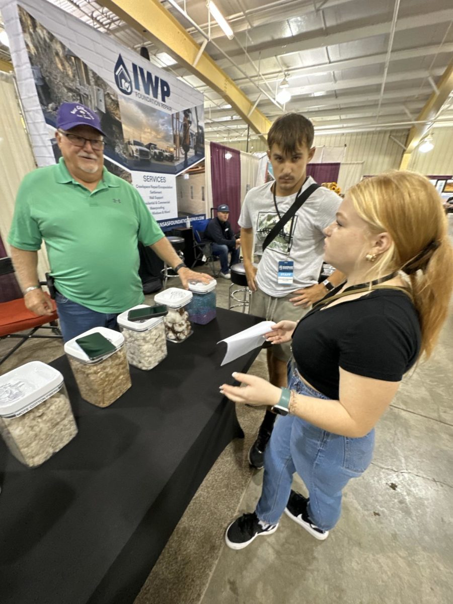 Juniors Lizzie Terry and Conor White interview an exhibitor at the State Fair on Sept. 11. They were assigned a story about the cotton industry for their print competition. 