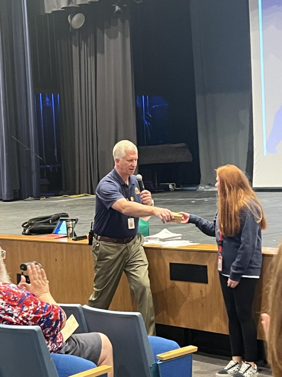 Head principal Eric Hofer-Holdeman hands the Good Apple award to paraprofessional Elizabeth Cox. Hofer-Holdeman is leaving Northwest after seven years